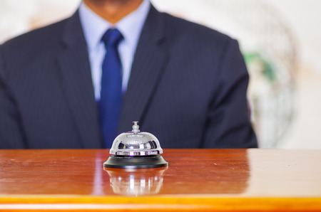 Elegant blue business suit standing behind desk bell at hotel reception.の写真素材