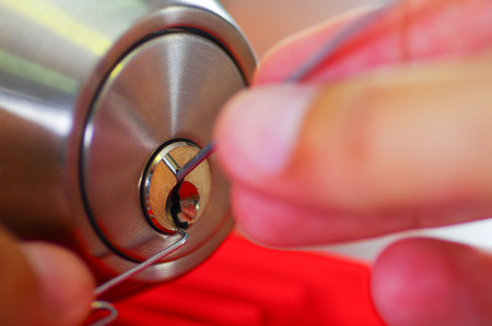 Closeup hands of locksmith using metal pick tools to open locked door.の写真素材
