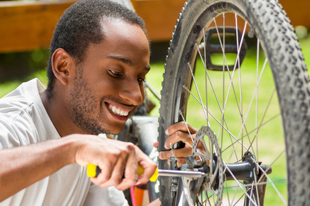 Man wearing white shirt happy working on repairing bicycle mechanics using screwdriver tool.の写真素材