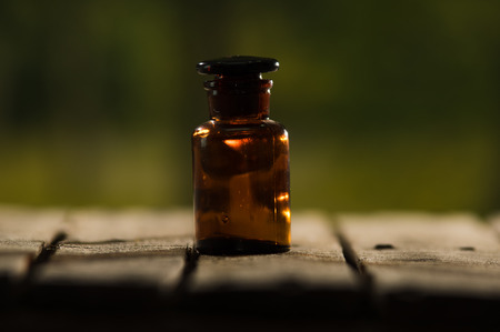 Small brown medicine bottle for magicians remedy sitting on wooden surface, beautiful night light setting, magic concept.の写真素材