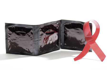 Closeup three pack of condoms standing on white surface facing camera, black packaging plastic, studio background, safe sex concept.の写真素材