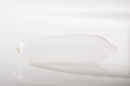 Closeup transparent condom filled with air lying on white surface, studio background, sexual safety concept,.の写真素材