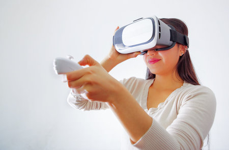 Young brunette woman wearing virtual reality goggles experiencing future technology, interacting and...