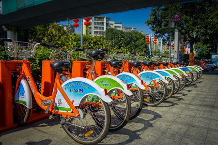 SHENZEN, CHINA - 29 JANUARY, 2017: City bike parking, row of orange bikes connected to automatic machines on city streetのeditorial素材
