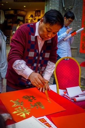 SHENZEN, CHINA - 29 JANUARY, 2017: Man painting on red decorative banner with golden letters, preparing for chinese new yearのeditorial素材