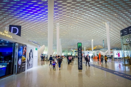 SHENZEN, CHINA - 29 JANUARY, 2017: Inside airport terminal connection halls, modern interior architecture design, glass mixed with white panels, shops restaurants and some people aroundのeditorial素材