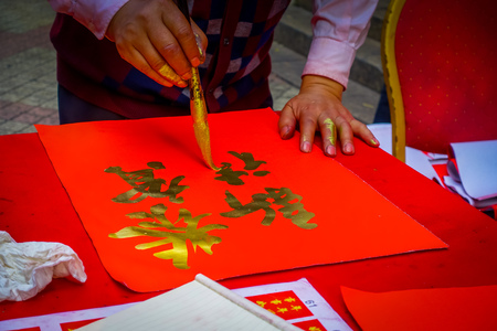 SHENZEN, CHINA - 29 JANUARY, 2017: Man painting on red decorative banner with golden letters, preparing for chinese new yearのeditorial素材