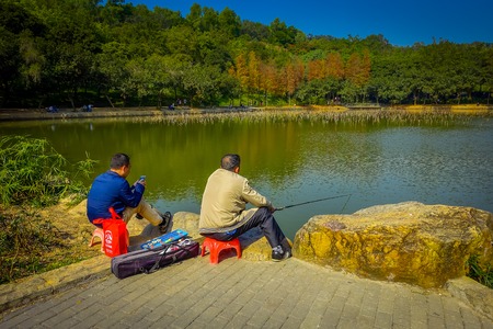 SHENZEN, CHINA - 29 JANUARY, 2017: Inside Lian Hua Shan park, large recreational area, people fishing in water lake sorrounded by trees, beautiful blue sky,のeditorial素材