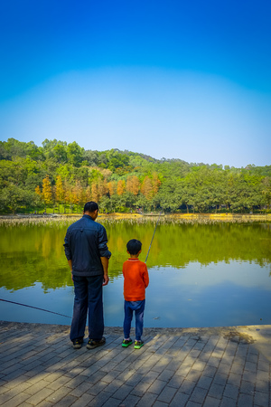 SHENZEN, CHINA - 29 JANUARY, 2017: Inside Lian Hua Shan park, large recreational area, people fishing in water lake sorrounded by trees, beautiful blue sky,のeditorial素材