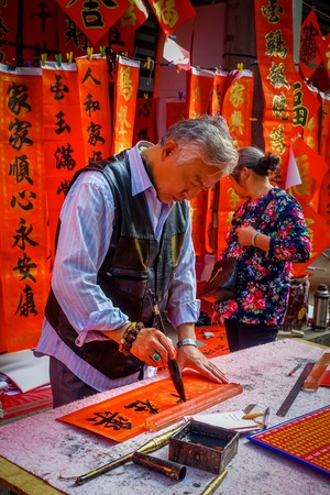SHENZEN, CHINA - 29 JANUARY, 2017: Man painting on red decorative banner with black letters, preparing for chinese new yearのeditorial素材