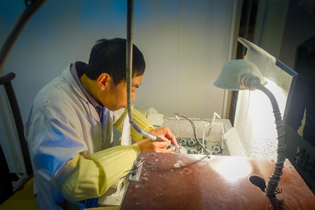 BEIJING, CHINA - 29 JANUARY, 2017: Jade craftsman sitting by desk using electric tool working with full concentration, traditional chinese art.のeditorial素材