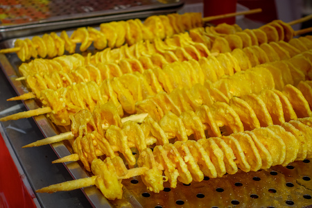 CHONGYUANG TEMPLE, CHINA: Delicious curly potato fries being prepared by chinese man at food market around temple areaの写真素材