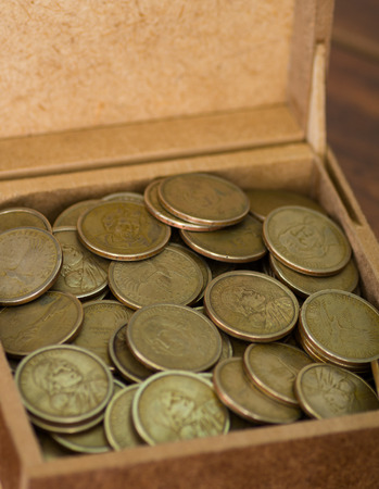Close up brown box filled with dollar coinsの写真素材