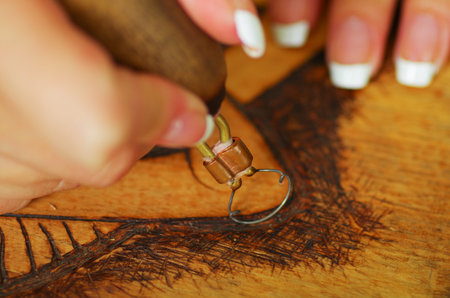 Close up shot of hands wood burning with pyrography pen