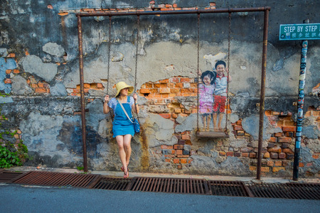 George Town, Malaysia - March 10, 2017: Unknown woman tourist and the Children on the Swing mural street art.のeditorial素材