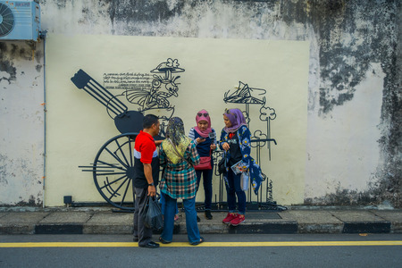 George Town, Malaysia - March 10, 2017: Unknown muslim tourists standing by Cannon graffiti, street art and iron sculpture in Cannon street.のeditorial素材