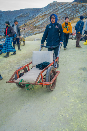 KAWEH IJEN, INDONESIA - 3 MARCH, 2017: Local miners using wheelbarrows to transport sulfur and equipment from mine located inside volcanic crater, high altitude landscapeのeditorial素材