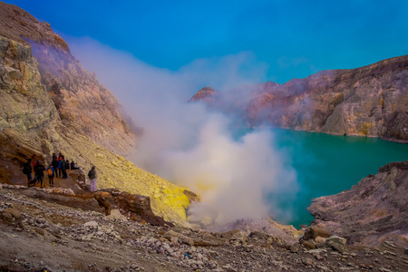 KAWEH IJEN, INDONESIA - 3 MARCH, 2017: Tourist hikers with backpacks and facial masks seen overlooking sulfur mine and volcanic crater lakeのeditorial素材