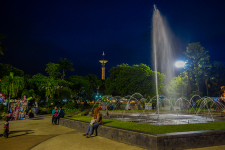 BANYUWANGI, INDONESIA: Charming park area with green vegetation and popular water fountain, people enjoying, beautiful blue evening sky in backgroundのeditorial素材