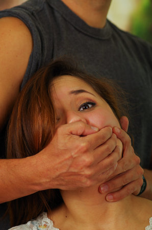 Man covering the mouth of a terrified young woman