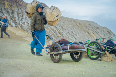 KAWEH IJEN, INDONESIA - 3 MARCH, 2017: Local miners using wheelbarrows to transport sulfur and equipment from mine located inside volcanic crater, high altitude landscapeのeditorial素材