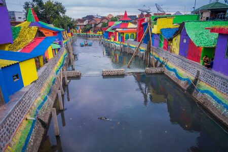 BANYUWANGI, INDONESIA: Water channel seen from bridge with colorful houses on both sides, charming neighborhood, cloudy skies in backgroundのeditorial素材