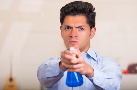 Handsome young caucasian male pointing cleaning spray bottle in front of himの写真素材