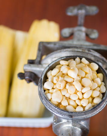A close up from a metalic mill with some corn kernelsの写真素材