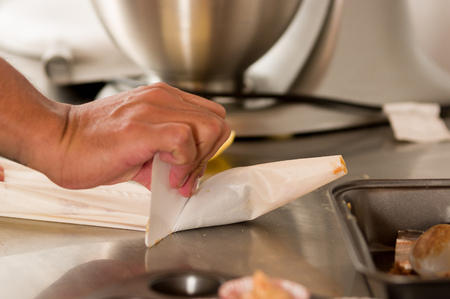 Bakery man manipulating the piping bag with some butter cream insideの写真素材