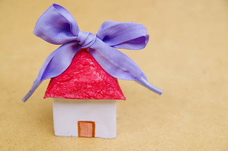 Little beautiful paper house with purple ribbon on wooden backgroundの写真素材