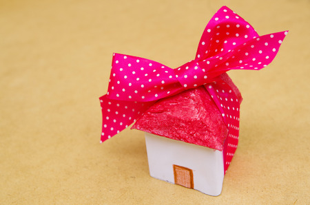 Little beautiful paper house with pink with white points ribbon on wooden backgroundの写真素材