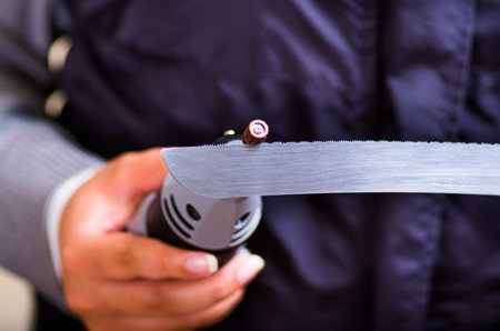 A hardworker woman using a polisher over a gray knife piece on a wooden background
