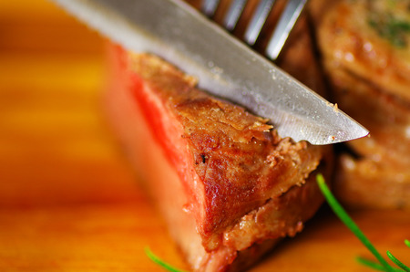 delicious succulent grilled meat on wooden table using kitchen utensilsの写真素材