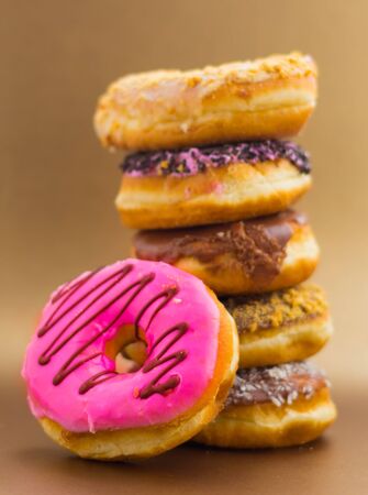Stack of assorted donuts in a soft brown backgroundの写真素材
