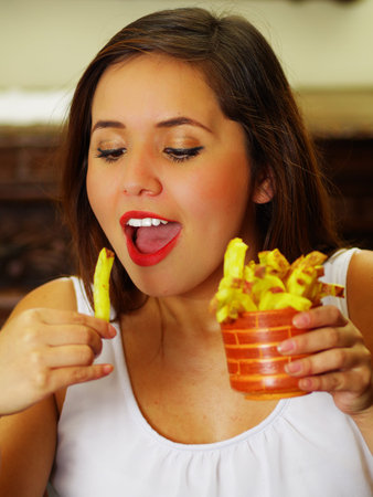 close up of a beauty woman in a restaurant eating a delicious french friesの写真素材