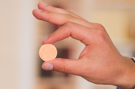 Close up of a man holding an effervescent tablet in his hand with blurred backgroundの写真素材