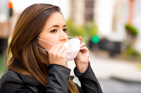 Close up of a young woman wearing a protective mask on the street in the city with air pollution,...