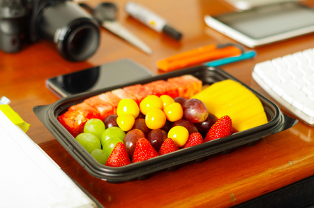 Close up of a healthy breakfast, fruit salad packed in plastic box on wooden tableの写真素材