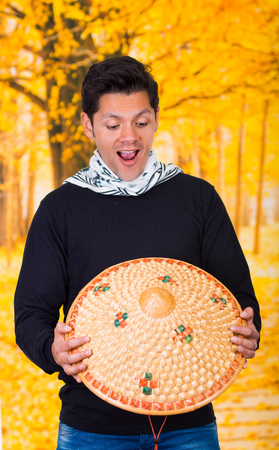 Portrait of a handsome hispanic young business guy holding an asian conical hat in autum backgroundの写真素材