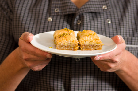 Man holding a delicious traditional turkish food baklava with pistachio in his handsの写真素材