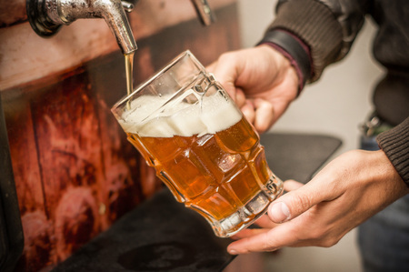 Bartender filling up with a blonde craft beer into a pint glassの写真素材