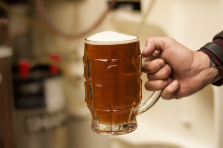 Delicious blonde craft beer filled into a pint glass on wooden tableの写真素材