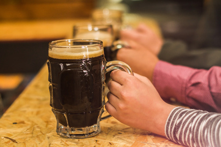 Close up of a male friends holding a craft beer in pubの写真素材