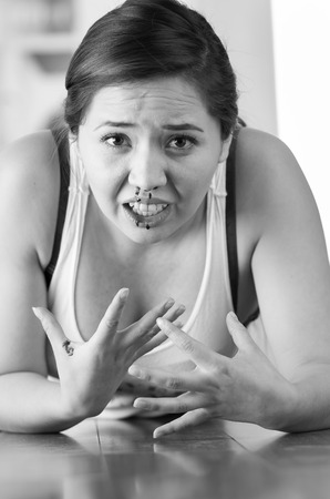 Beautiful woman nosebleed, woman is bleeding from her nose on wooden floor, black and white effectの写真素材