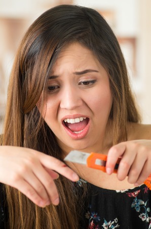 Beautiful young woman injured her finger with an orange cutterの写真素材