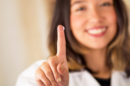 contact lens on finger and beautiful woman smiling behind on gray background