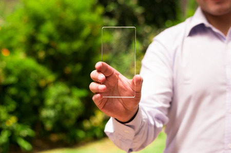 Businessman holds futuristic transparent smart phone in his handの写真素材
