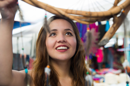 Beautiful smiling woman looking a blurred cardreams in the andean traditional clothing and handicrafts, market backgroundの写真素材