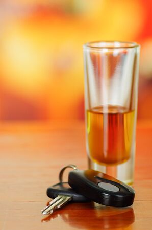 Close up of a shoot of tequila with car keys on wooden table with a blurred backgroundの写真素材