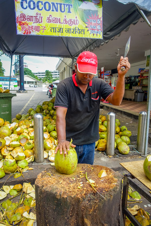 Kuala Lumpur, Malaysia - March 9, 2017: Unknown street vendor person cutting and selling fresh coconut to tourists.のeditorial素材